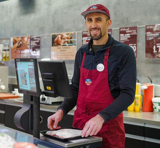 Person arbeitet an der Kassa eines Supermarkts im Rahmen eines Arbeitsintegrationsprojekts
