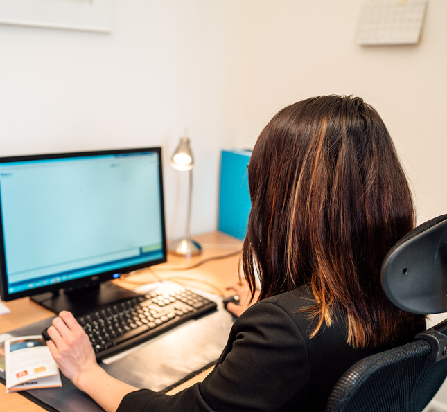 Person sitzt am Schreibtisch und nutzt einen Computer für eine vertrauliche Onlineberatung bei seelischen Belastungen.