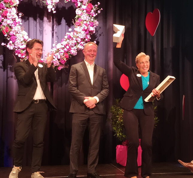 Eine Gewinnerin des VITA Awards steht auf der Bühne und streckt stolz ihren Preis in die Luft.
