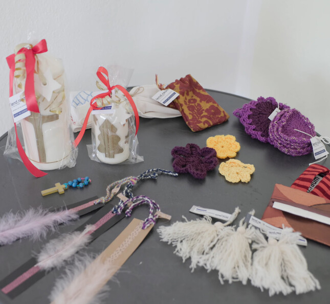 Auf einem Tisch liegen Kerzen, Textilien und Dekorationen aus handwerklicher Arbeit in Beschäftigungsprojekten