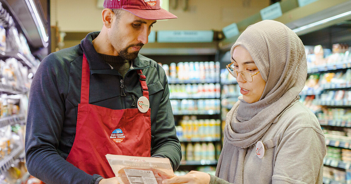Zwei Personen besprechen ein Produkt in einem Supermarkt im Rahmen eines begleiteten Arbeitseinsatzes.