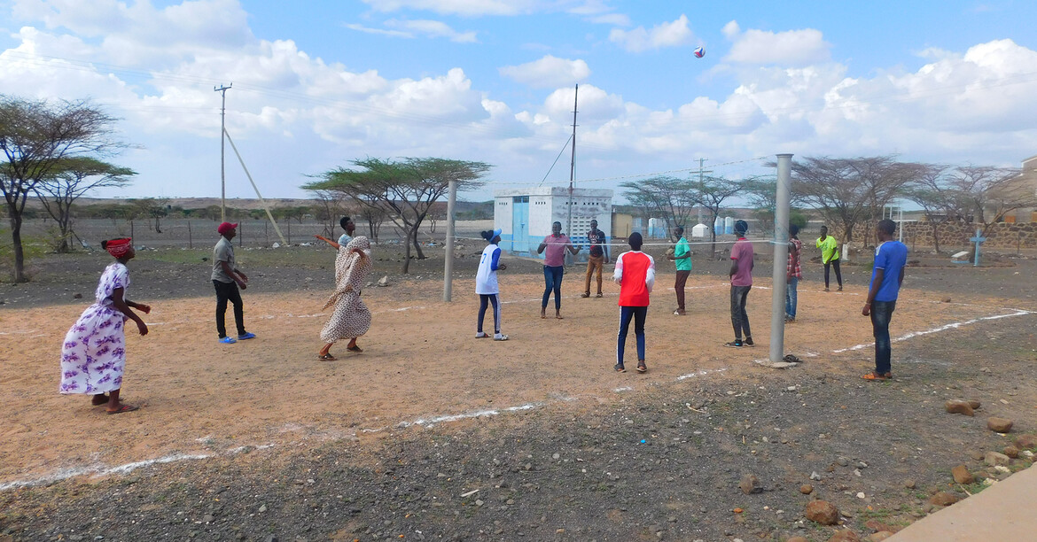 Eine Gruppe von afrikanischen Menschen spielt gemeinsam Volleyball.