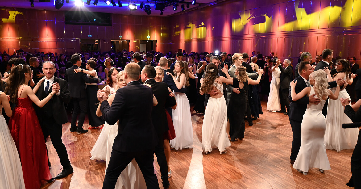 Viele Paare in schwarzen und weißen Kleidungen tanzen die Polonaise.