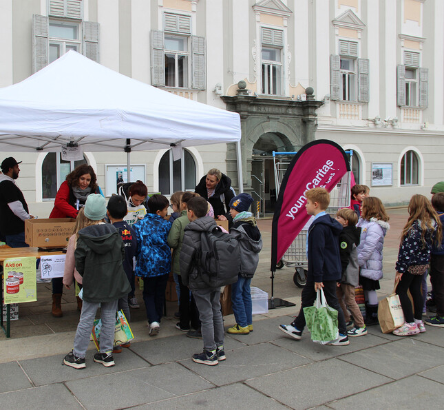 Schüler*innen stellen sich vor einem weißen Zelt an um Lebensmittelspenden abzugeben.