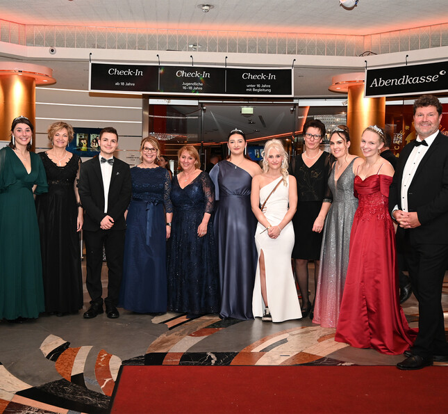 Schüler*innen und Lehrer*innen stehen gemeinsam mit Caritasdirektor Sandriesser in Abendgarderobe im Foyer des Casino Veldens beim HLW Maturaball.