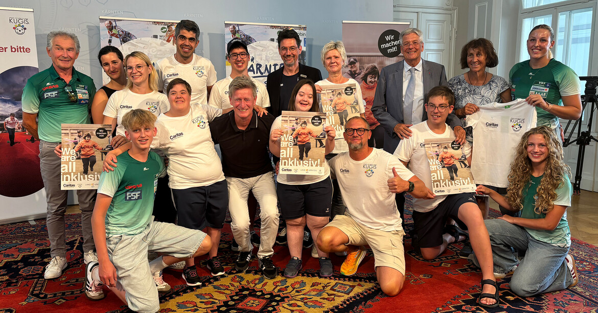 Klient*innen und Betreuer*innen des Sportbereiches KUGIS unseres Bereiches Menschen in Not posieren mit dem Land für das gemeinsame Projekt.