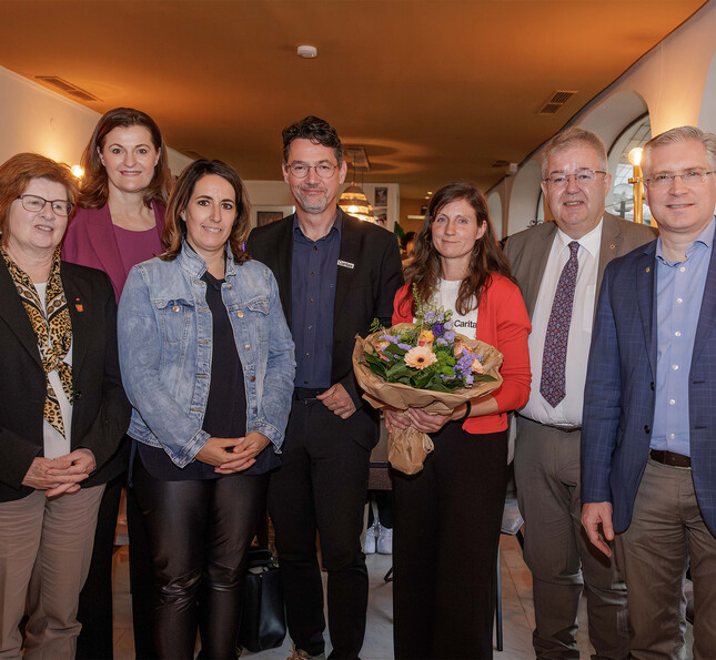 Gruppe von Kooperationspartner*innen steht bei einer Veranstaltung der RegionalCaritas in einem Innenraum