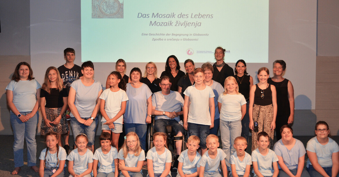 Gruppe von Darsteller*innen steht gemeinsam auf einer Bühne während eines Theaterstücks.