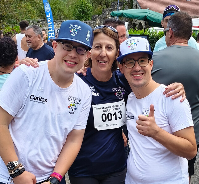 Drei Teilnehmer*innen mit Startnummern posieren gemeinsam beim Friesacher Charity Run.